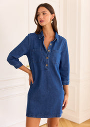 Robe Nesta en denim bleu portée de face, avec une main dans la poche latérale.