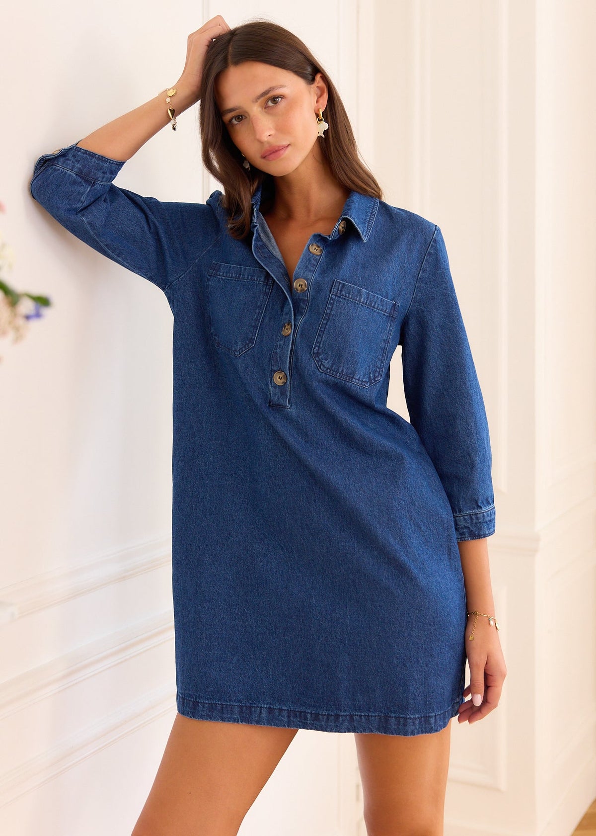 Robe Nesta en denim bleu à manches trois-quarts, portée de face, un bras relevé.