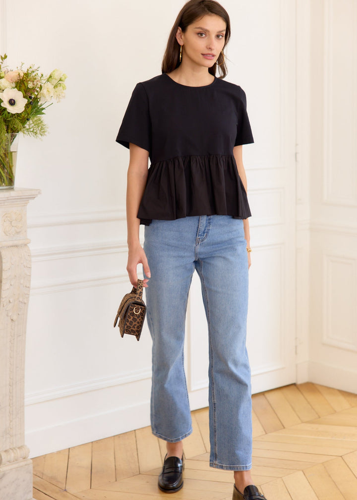 Top péplum noir porté avec un jean.