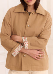 Veste beige coton doublure Liberty — gros plan du col et des boutons, bras croisés