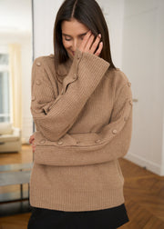 Pull camel porté, bras croisés montrant les boutons des manches