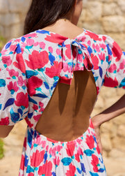 Détail du nœud et du dos ouvert d’une robe fleurie rose et bleue.