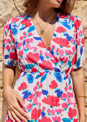 Détail du décolleté croisé en V et du tissu d’une robe fleurie rose et bleue.