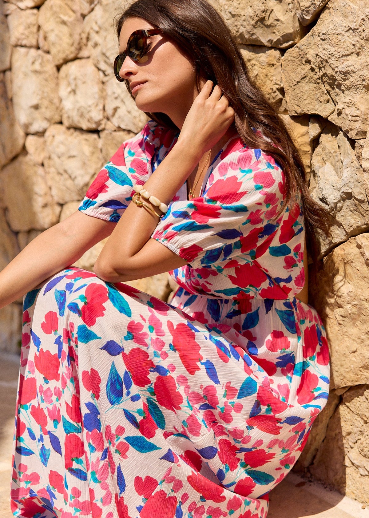 Robe fleurie rose et bleue sur fond clair, portée assise de profil.