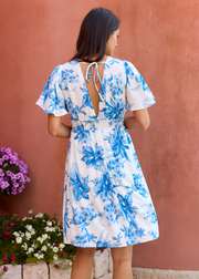 Robe blanche à fleurs bleues, vue de dos avec ouverture et liens à nouer à la nuque.