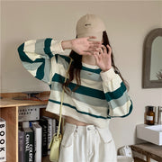 Pull coupe ample Louane vert rayé — vue portée de face, devant des étagères en bois
