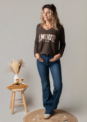 Pull col V texturé porté par une femme, silhouette entière, pull marron, jean flare, de face
