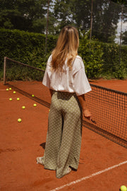 Pantalon fluide à pois porté par une femme, vue de dos, filet, tennis