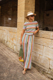 Pantalon crochet taille haute porté par une femme, silhouette entière, muret en pierre, chapeau de paille