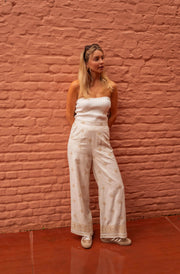 Pantalon à motifs effet lin porté par une femme, vue de face, mur en brique, top bandeau