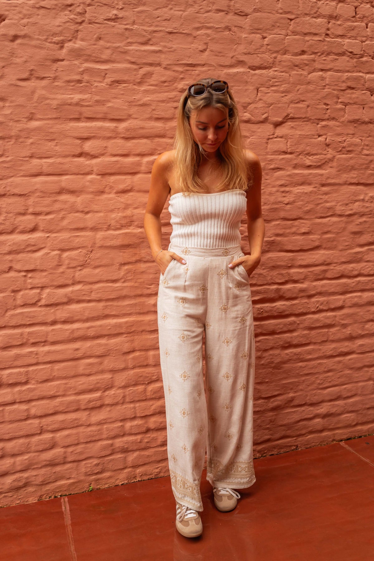 Pantalon à motifs effet lin porté par une femme, silhouette entière, mur en brique, top blanc
