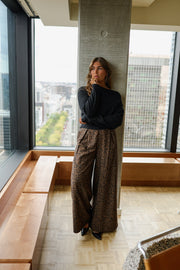Pantalon fluide léopard porté par une femme, silhouette entière, haut noir, pilier