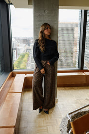 Pantalon fluide léopard porté par une femme, silhouette entière, pilier, sourire