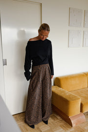 Pantalon fluide léopard porté par une femme, silhouette entière, salon, haut noir