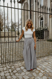 Pantalon à pinces rayé loose porté par une femme, silhouette entière, grille, de face