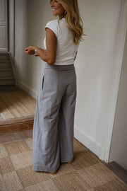 Pantalon à pinces rayé loose porté par une femme, vue de profil, haut blanc
