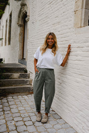 Pantalon barrel légèrement court porté par une femme, silhouette entière, t-shirt blanc, escalier
