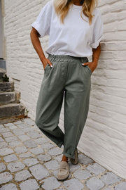 Pantalon barrel légèrement court porté par une femme, silhouette entière, t-shirt blanc, mains dans les poches