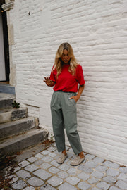 Pantalon barrel légèrement court porté par une femme, silhouette entière, haut rouge, pavés