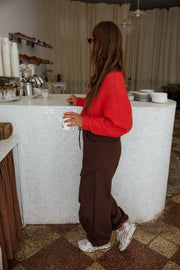 Pantalon cargo à poches latérales porté par une femme, vue de dos, pull rouge, gobelet