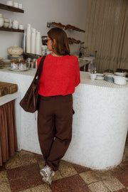 Pantalon cargo à poches latérales porté par une femme, vue de dos, sac, pull rouge