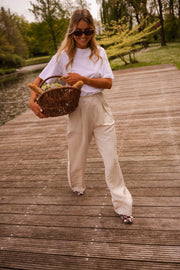 Pantalon fluide en lin beige porté par une femme, vue de trois-quarts, ponton, panier