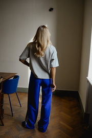 Pantalon à bandes et cordon porté par une femme, vue de dos, table en bois, parquet