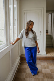 Pantalon à bandes et cordon porté par une femme, silhouette entière, couloir, fenêtres