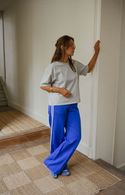 Pantalon à bandes et cordon porté par une femme, vue de trois-quarts, mur blanc, carrelage