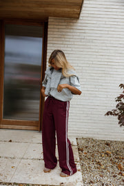 Pantalon à bandes latérales porté par une femme, silhouette entière, porte vitrée, de loin