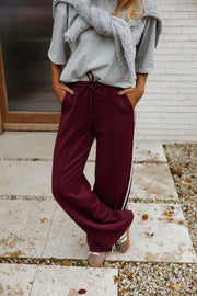 Pantalon à bandes latérales porté par une femme, silhouette entière, mains dans les poches