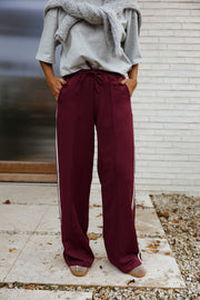 Pantalon à bandes latérales porté par une femme, vue de trois-quarts, main dans la poche