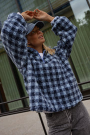Veste polaire à carreaux portée par une femme, vue rapprochée, mains sur la casquette