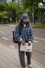Veste polaire à carreaux portée par une femme, vue de trois-quarts, journal à la main, autre cadrage