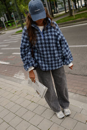 Veste polaire à carreaux portée par une femme, vue de trois-quarts, journal à la main