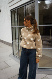 Veste polaire à cœurs portée par une femme, vue de face, baie vitrée, jean large