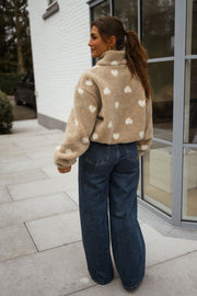 Veste polaire à cœurs portée par une femme, vue de dos, baie vitrée, cheveux bruns