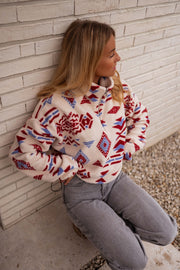 Polaire zippée à motifs écrue portée par une femme, vue de face, mur blanc, jean