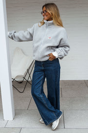Veste polaire zippée chaude portée par une femme, vue de face, chaise pliante, jean large
