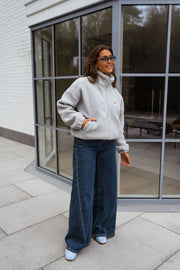 Veste polaire zippée chaude portée par une femme, vue de trois-quarts, baie vitrée, jean large