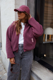 Veste polaire doublée à capuche prune portée par une femme, vue de trois-quarts, mains dans les poches