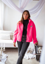 Gilet polaire chaud à poches rose porté par une femme, silhouette entière, salon, canapé