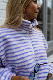 Veste polaire rayée zippée portée par une femme, vue rapprochée, col montant zippé, lunettes accrochées
