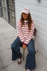 Polo loose à col revers porté par une femme, assise, chaise blanche, casquette rose