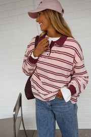 Polo loose à col revers porté par une femme, vue de trois-quarts, casquette rose, main sur le col