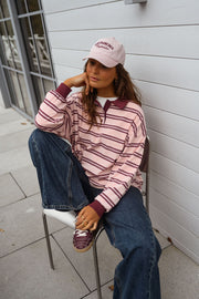 Polo loose à col revers porté par une femme, assise, chaise blanche, jambe repliée