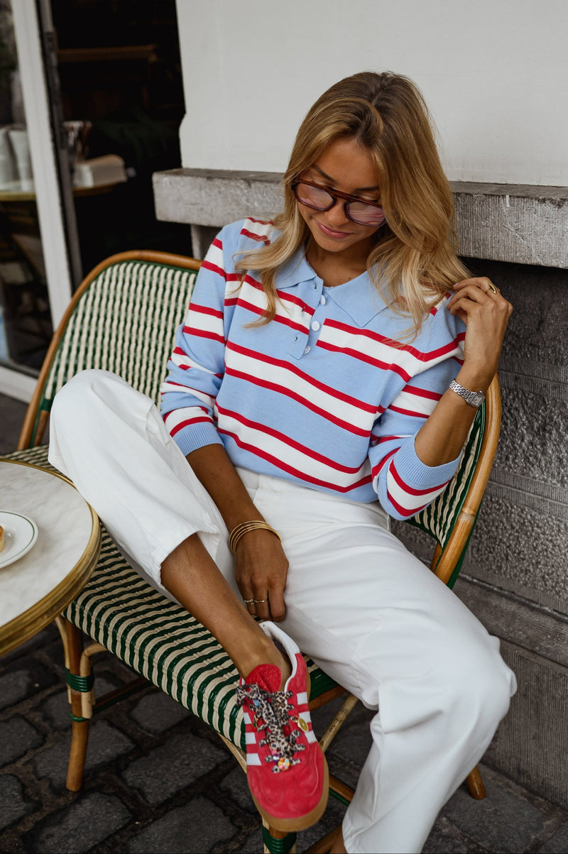 Polo rayé col boutonné porté par une femme, assise, chaise de terrasse, baskets rouges