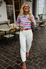 Polo rayé col boutonné porté par une femme, vue de face, terrasse, jean blanc
