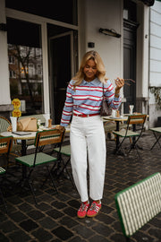 Polo rayé col boutonné porté par une femme, vue de face, terrasse, baskets rouges