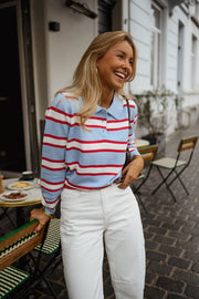 Polo rayé col boutonné porté par une femme, vue de trois-quarts, terrasse, main dans les cheveux